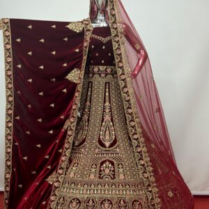 Maroon velvet bridal lehenga with heavy golden embroidery displayed on mannequin showing full spread of the skirt and dupatta